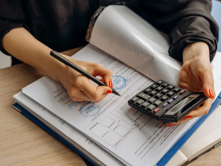 Mãos a escrever leituras num caderno, com uma calculadora ao lado